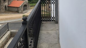 A balcony with a black metal railing overlooking a church with a bell tower and a red-tiled roof. - Room 'Habitación Selvita' with Mountain View, Shared Terrace and Wi-Fi (Moraime)