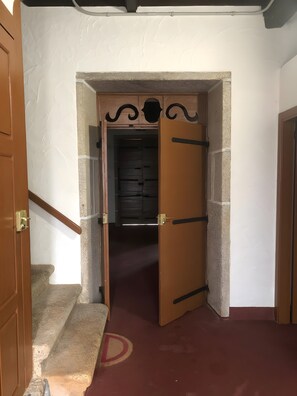 Ein Flur mit einer Holztür, die zu einem Zimmer mit dunklem Innenraum führt.