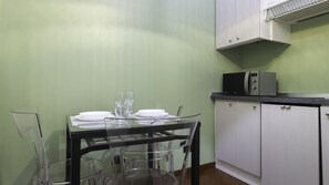 A dining area with a table set for two, a microwave, and a cabinet. - Italianway Easy - Venezia 33 - B (Milan)