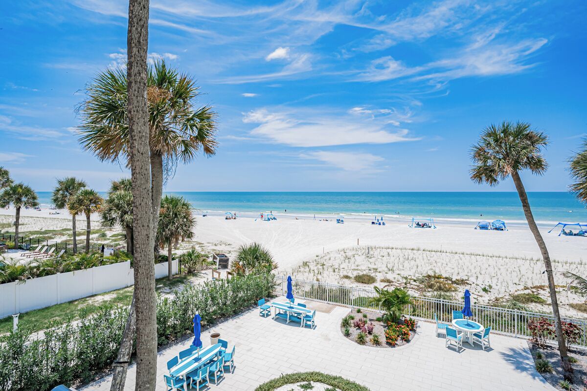 A beachside resort with a patio area featuring outdoor seating and a view of the ocean.