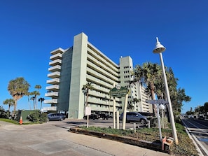 Un edificio de gran altura con varios balcones, una farola y un cartel que indica Sand Castle Condominiums.