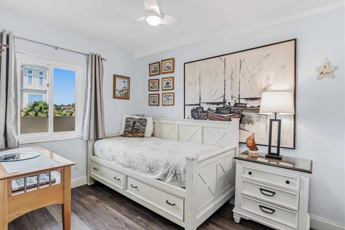 Une chambre à coucher avec un lit, une table de chevet, une lampe et une œuvre d’art accrochée au mur.
