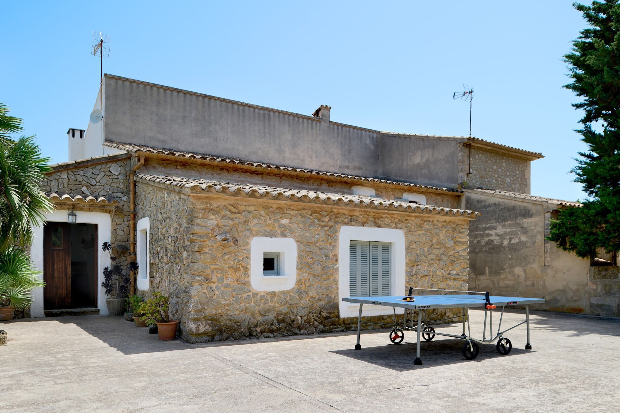 A stone building with a flat roof, a door, and a window. There is a table with wheels in front of the building.