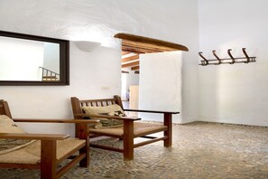 Ein Zimmer mit Holzstuhl, Holztisch, Spiegel und einem an der Wand befestigten Kleiderhaken.