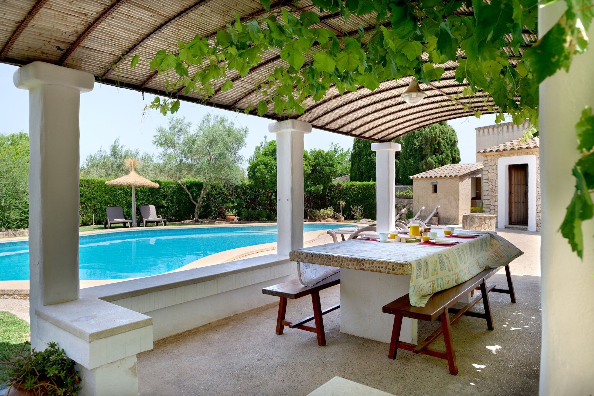 A covered outdoor area with a pool, seating, and a table with breakfast items.