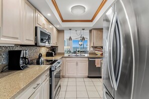 A modern kitchen with stainless steel appliances, a microwave, a coffee maker, and a kettle. - Gulf Front Getaway! Sand Castle I 307 (Indian Shores)