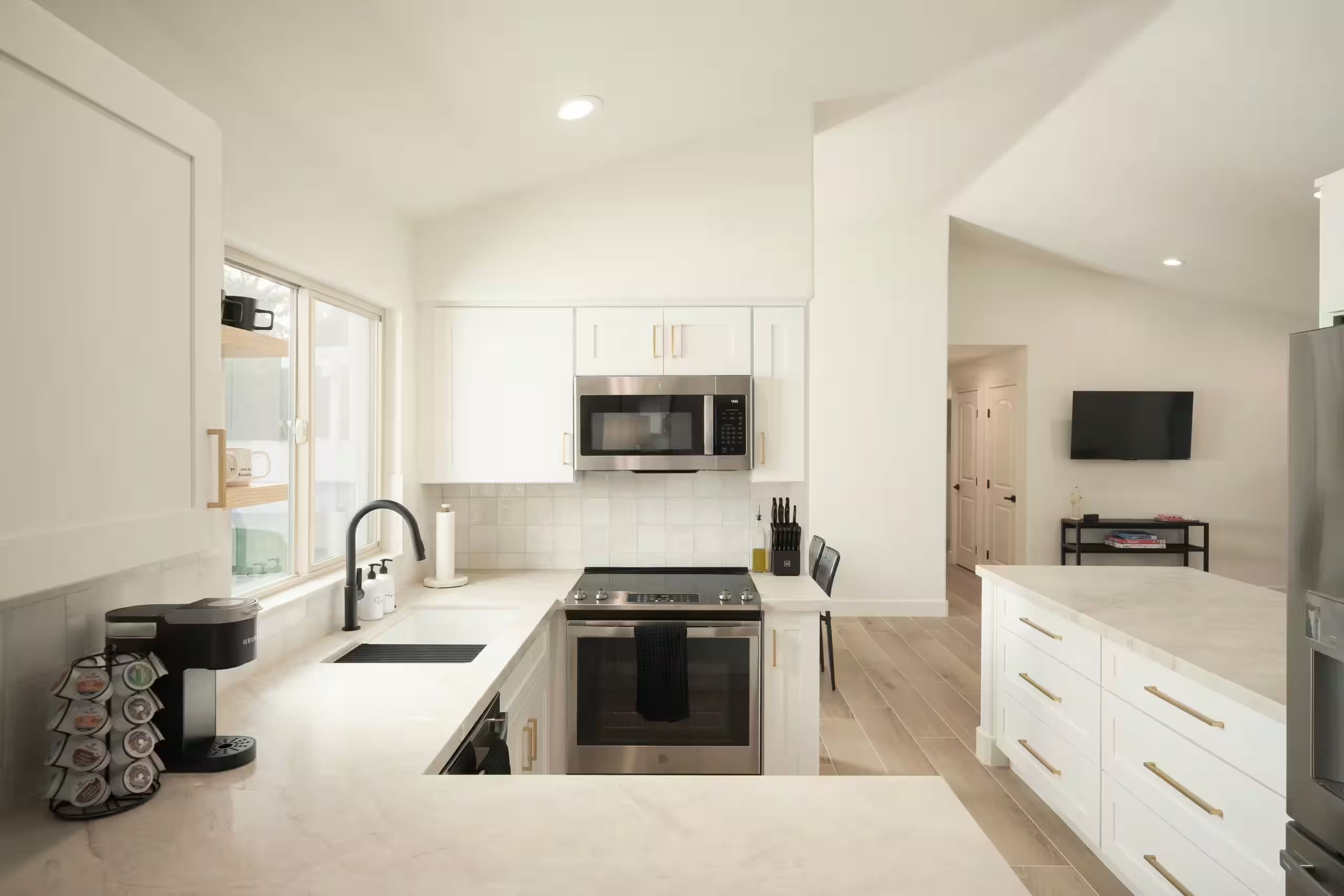A modern kitchen with white cabinetry, a stainless steel range, and a built-in microwave.