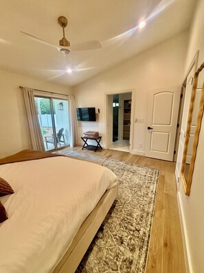 A bedroom with a bed, a ceiling fan, a television, and a sliding glass door leading to an outdoor area. - Desert Bliss Villa - 3 bedroom Heated Pool, Putting Green, Pool Table & Games (Phoenix)