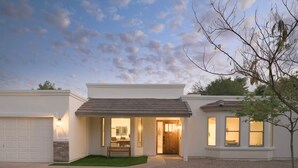 Ein modernes, zweistöckiges Haus mit Garage, überdachter Terrasse und gepflegtem Rasen.
