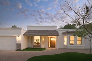 Ein modernes, zweistöckiges Haus mit Garage, überdachter Terrasse und gepflegtem Rasen.