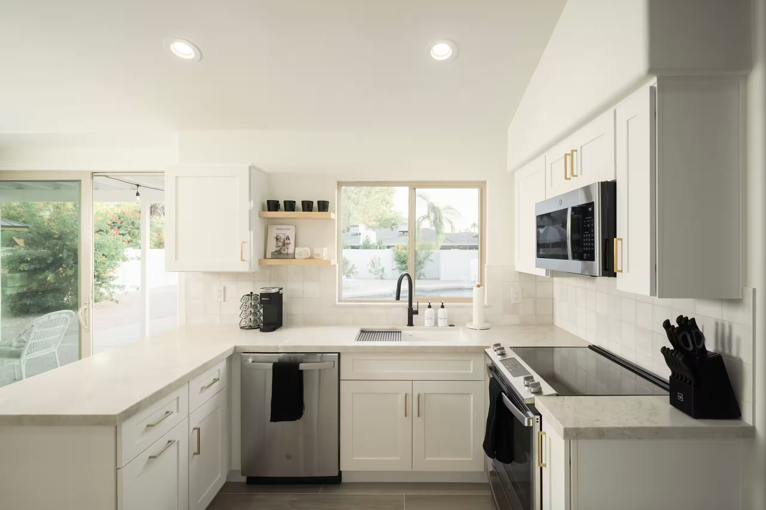 A modern kitchen with white cabinetry, a built-in oven, a microwave, and a dishwasher.