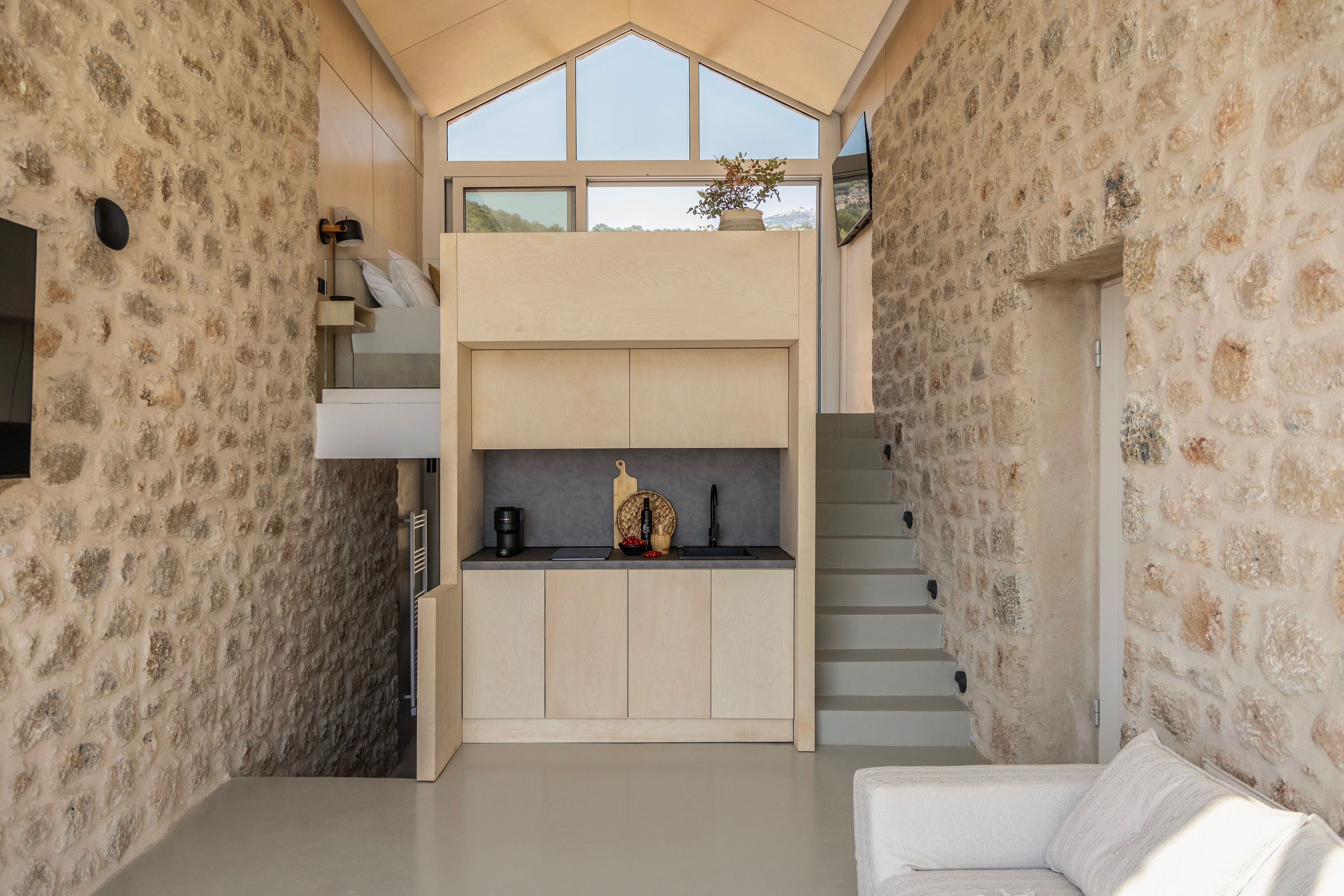 Un espacio habitable compacto con cocina, escalera y zona de estar.