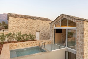 A stone building with a glass-enclosed pool and a door leading to a room.