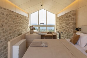 A bedroom with a large window, a bed, a desk, and a radiator.