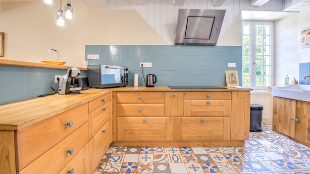 Una cucina con mobili in legno, forno a incasso e pavimento in piastrelle decorate.