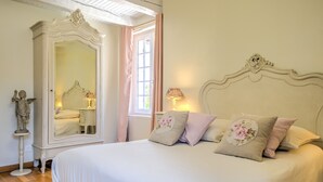 Una camera da letto con un letto grande, una cassettiera, uno specchio e una finestra con tende.