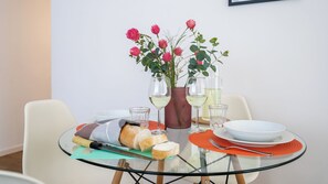 Ein Esstisch mit Glasplatte, eine Vase mit rosa Blumen und Weingläsern.