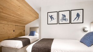 Ein Schlafzimmer mit zwei Betten, einer Holzbalkendecke und drei gerahmten Bildern an der Wand.