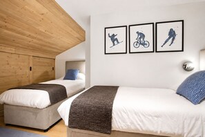 Ein Schlafzimmer mit zwei Betten, einer Holzbalkendecke und drei gerahmten Bildern an der Wand.