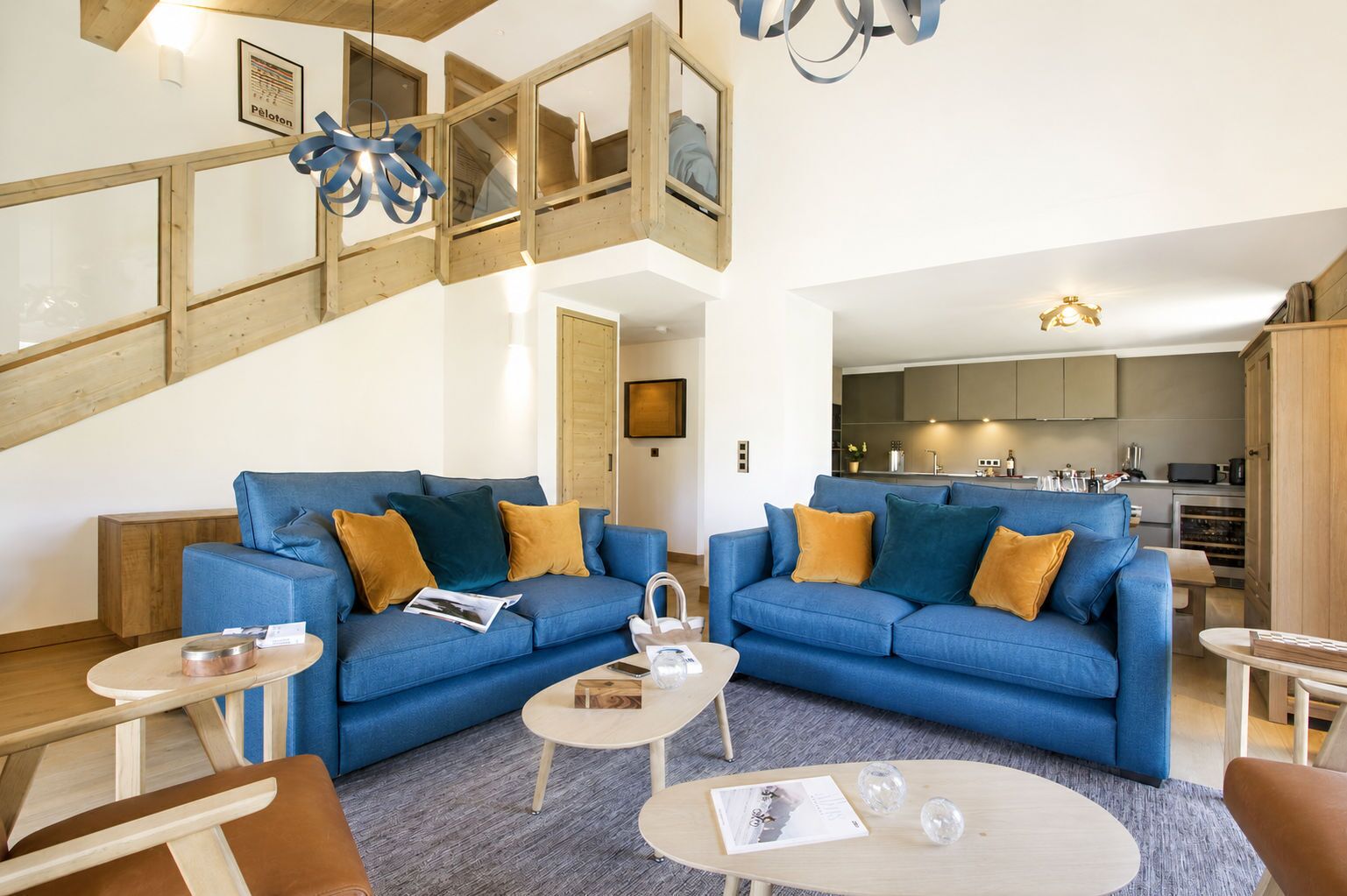 Ein modernes Wohnzimmer mit blauer Sofagarnitur, Holzboden und einer Treppe, die zu einer oberen Ebene führt.