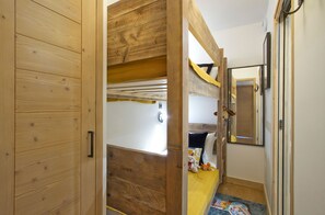 A room with a bunk bed, wooden walls, a door with a handle, and a small window. - Duplex ski aux pieds | Piscine intérieure & sauna (Alpe d'Huez)