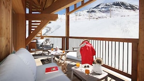 Eine Holzterrasse mit Blick auf eine verschneite Berglandschaft.