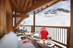 Eine Holzterrasse mit Blick auf eine verschneite Berglandschaft.