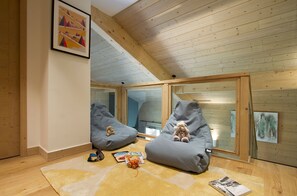 Et værelse med trælofter, to sækkestole, en bamse og et tæppe.