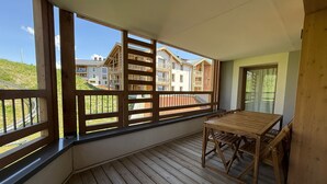 Ein Balkon mit einem Holztisch und Stühlen, Blick auf Gebäude und einen klaren Himmel.
