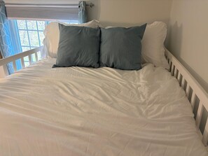 A bed with white bedding and two pillows, a window with curtains, and a white railing. - Lovely 3-bedroom townhome with AC in vibrant Arlington (Arlington)