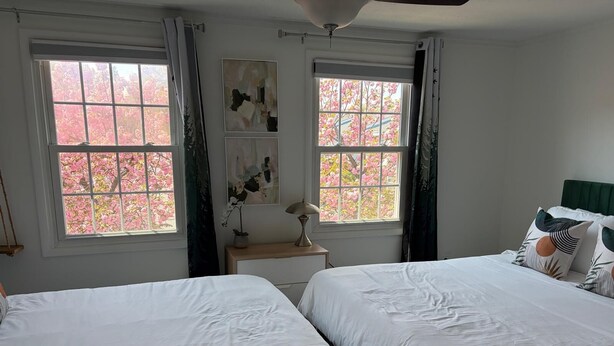 Una habitación con dos camas, una mesita de noche, una lámpara y una ventana con cortinas.