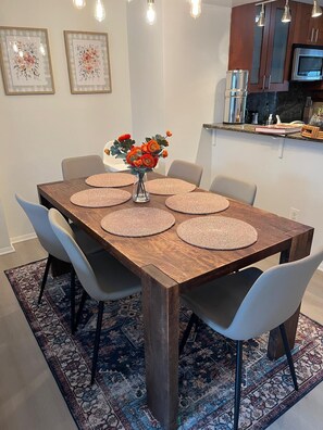 A dining table with six chairs, a vase with flowers, and a kitchen in the background. - Lovely 3-bedroom townhome with AC in vibrant Arlington (Arlington)