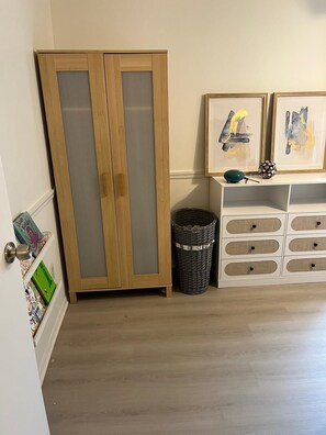 A room with a wooden wardrobe, a white storage unit with drawers, and a wicker basket on the floor. - Lovely 3-bedroom townhome with AC in vibrant Arlington (Arlington)