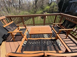 Une terrasse en bois avec une table et des chaises, entourée d’une rambarde.