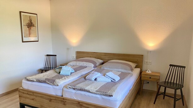 Ein Doppelbett mit Holzrahmen, zwei Nachttische und ein Sessel.