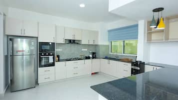 Una cocina moderna con electrodomésticos de acero inoxidable, armarios blancos y encimera negra.
