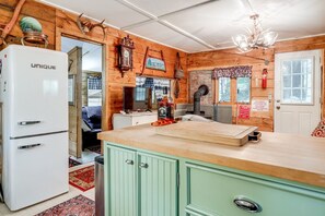 A rustic kitchen with a white refrigerator, a green cabinet, and a wooden ceiling.