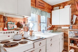 Una cocina con estufa, lavamanos y armarios de madera.