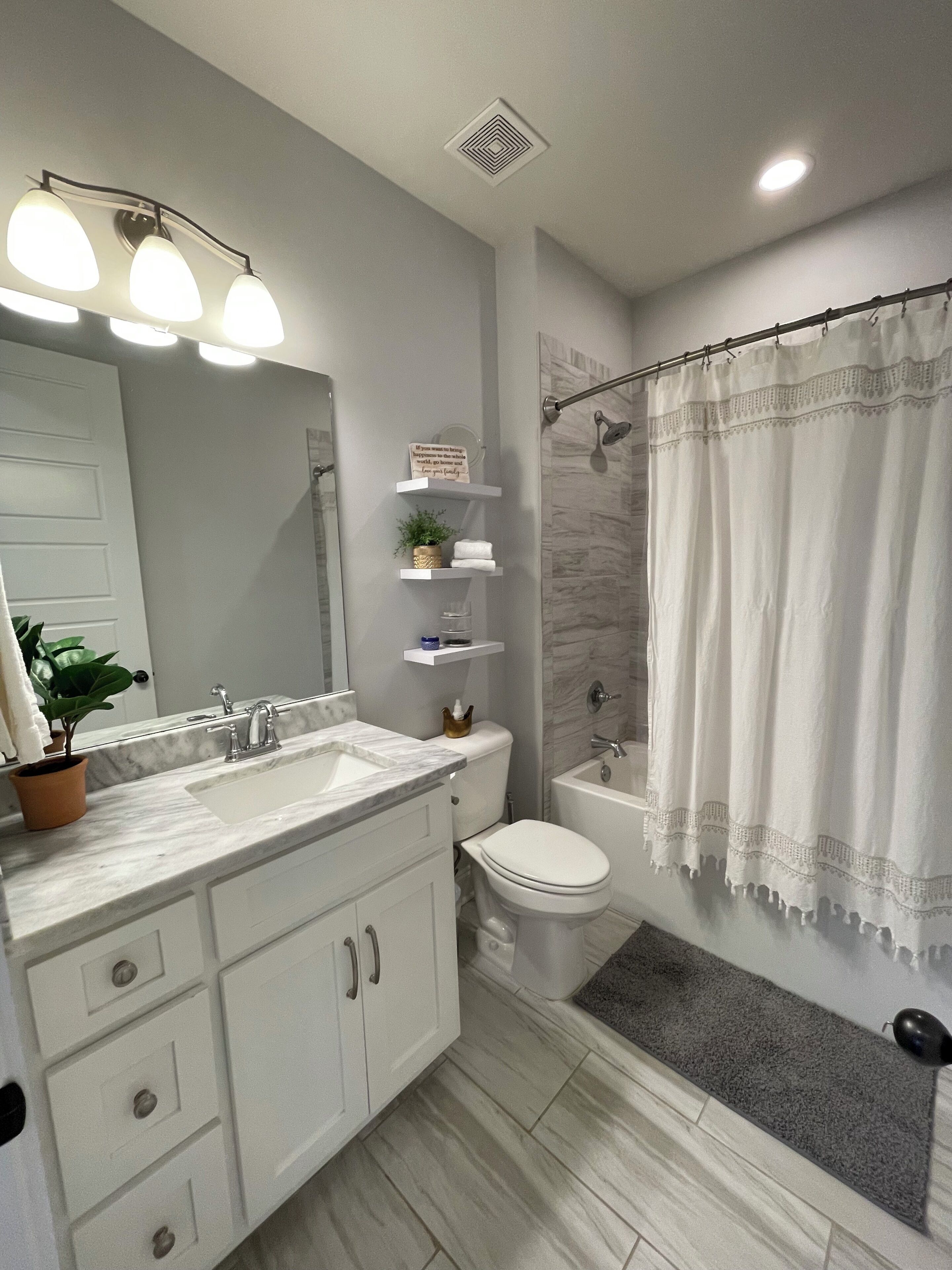 Un baño moderno con lavamanos, espejo, inodoro y zona de ducha.
