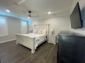 A bedroom with a bed, nightstands, a dresser, a ceiling fan, and a mounted TV. - Charming 3-bedroom house in beautiful Oxford. (Oxford)