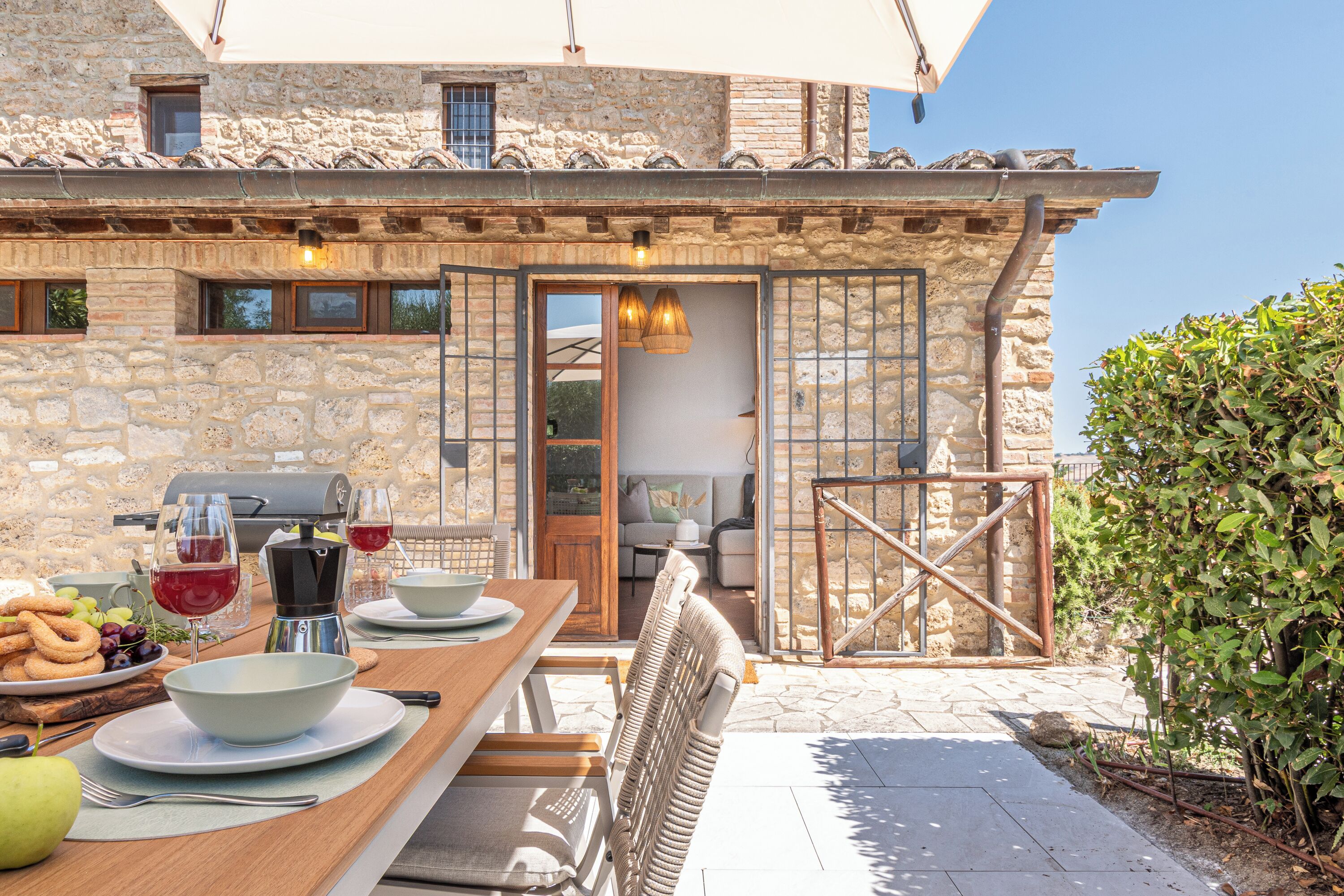 A stone building with a wooden deck, outdoor seating, and a grill.