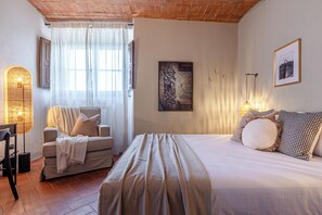 A bedroom with a bed, a chair, a lamp, and a picture on the wall. - New Apartment in Tuscany with a Pool and Breathtaking Views (Asciano)