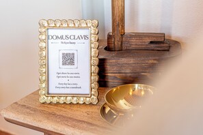 A framed sign with a QR code and text, placed on a wooden surface next to a brass bowl. - New Apartment in Tuscany with a Pool and Breathtaking Views (Asciano)