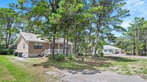 A two-story house with a front porch, surrounded by trees. - Ash at the Beach (Santa Rosa Beach)