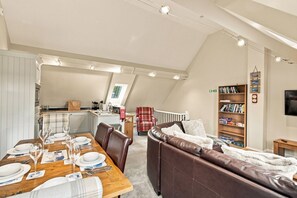 A modern loft-style living space with a dining area, a cozy seating area, and a kitchen. - 5 Old Templars - North East Escapes (Spittal)