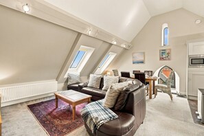 A loft-style living room with a high ceiling, a dining area, and a kitchen. - 5 Old Templars - North East Escapes (Spittal)