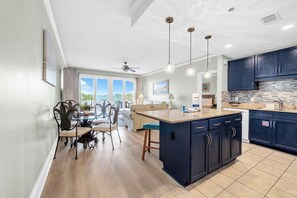 A modern kitchen with dark cabinets, a central island, and pendant lighting. - Laketown Wharf 329 (Panama City Beach)