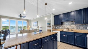 Une cuisine moderne avec des meubles de couleur bleu foncé, un plan de travail en granit et une vue sur l’extérieur.