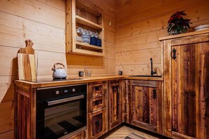 A wooden kitchen with a built-in oven, a kettle, and a shelf with cups. - Holiday home in Podhale, jacuzzi, sauna (Murzasichle)