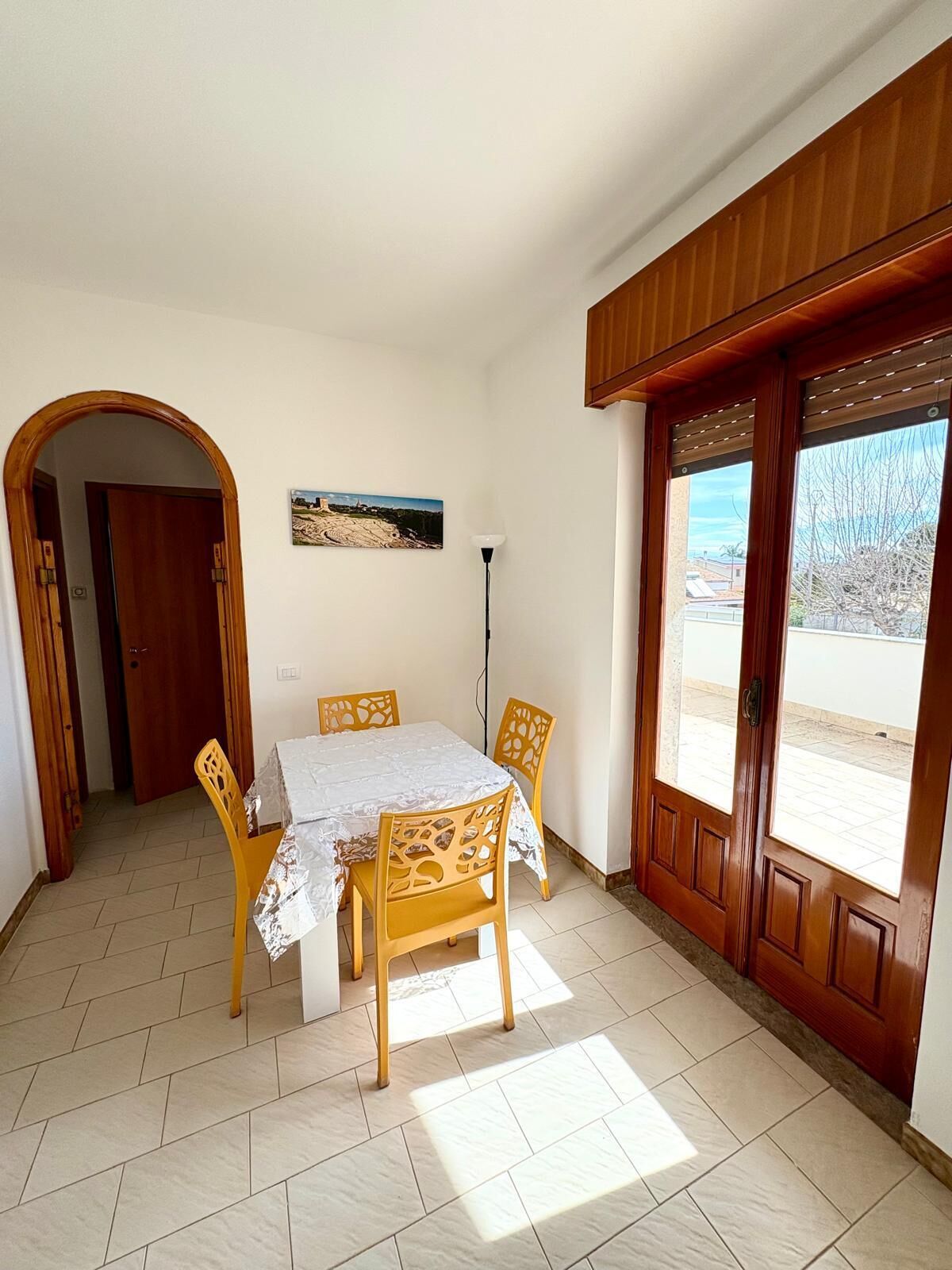 Un coin repas avec une table et des chaises, un tableau accroché au mur et une vue à travers la porte.